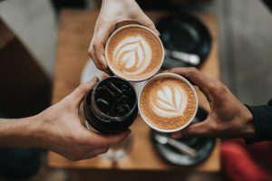 Three people holding hot and iced coffee.