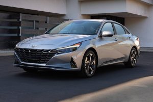 A silver 2022 Hyundai Elantra parked in front of a modern home in the driveway.