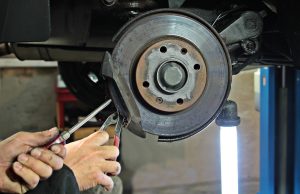 A mechanic working on the brake pad of a vehicle.